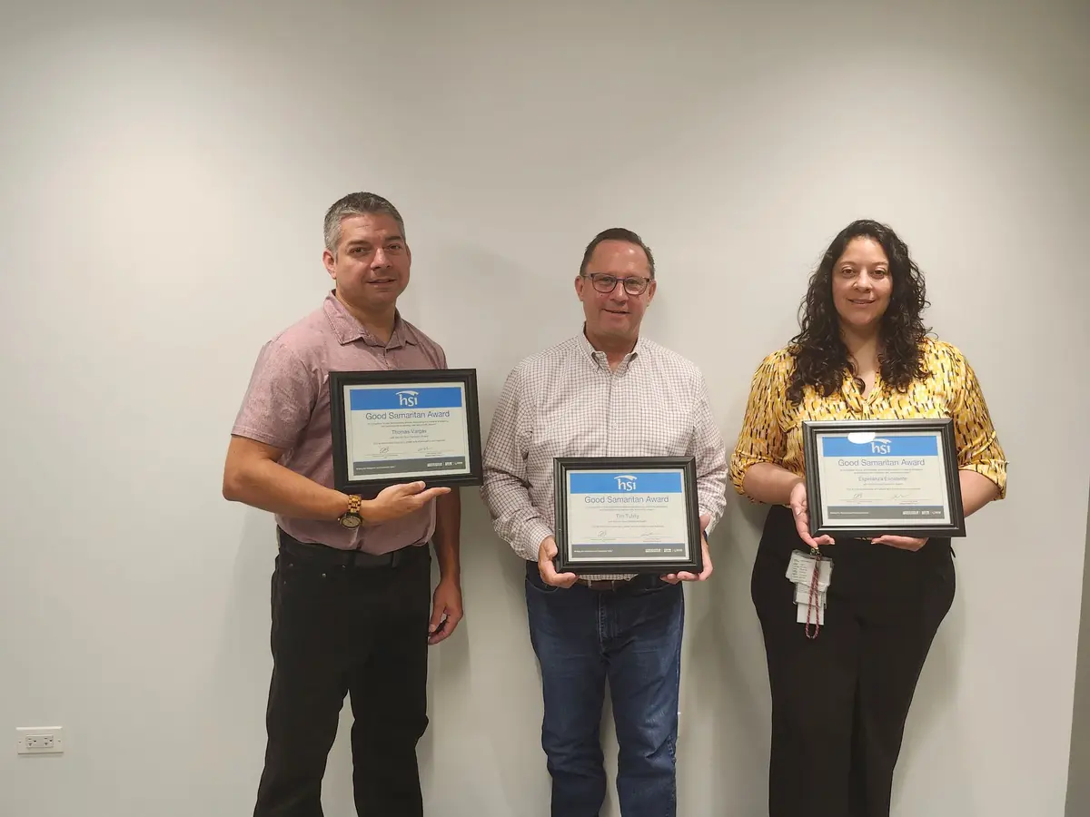 Four people standing together with framed certificates